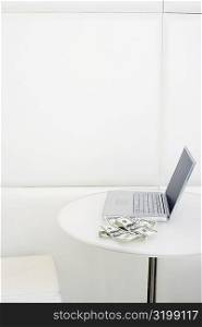 High angle view of laptop with dollar bill on the table