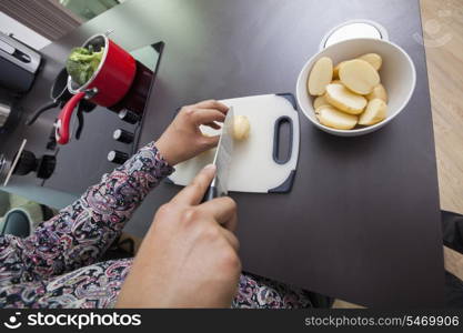 High angle view of man cutting potato at kitchen counter