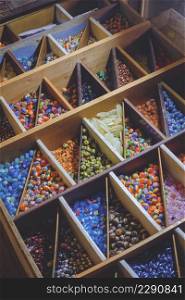 High angle view of many various colorful beads in wooden storage box in vertical frame