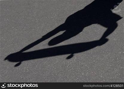 High angle view of shadow of a person holding a skateboard