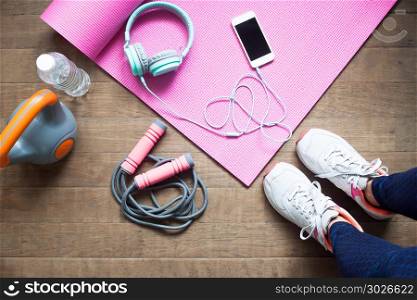 High angle view of sporty woman with fitness equipment and smart. High angle view of sporty woman with fitness equipment and smartphone on wooden floor, Diet and fitness