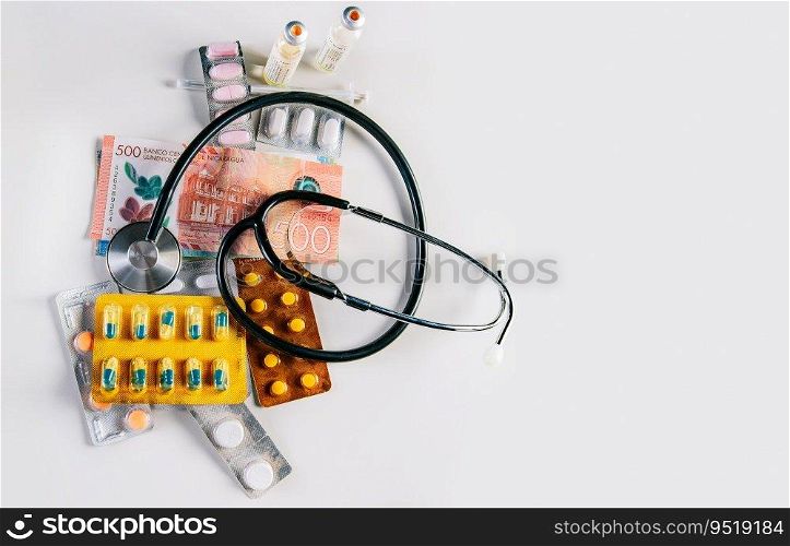 High angle view of stethoscope with pills on money isolated. Stethoscope with medicaments on Nicaraguan Cordobas. High cost of medical health with stethoscope