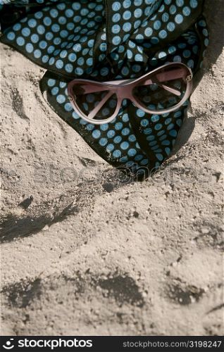 High angle view of sunglasses with a towel on the sand