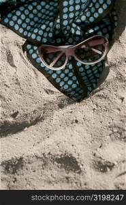 High angle view of sunglasses with a towel on the sand