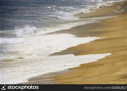 High angle view of surf flowing on the beach