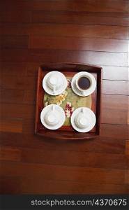 High angle view of tea cups with a tray on a hardwood floor