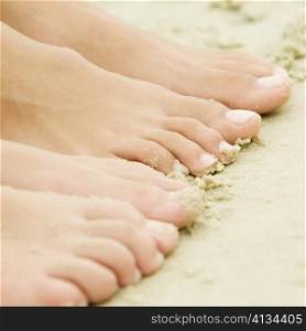 High angle view of the feet of two people on sand