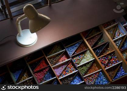 High angle view of the old retro desk l&with various colorful beads in wooden storage box on step table