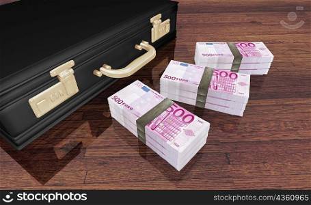 High angle view of three bundles of five hundred Euro bank notes near a briefcase