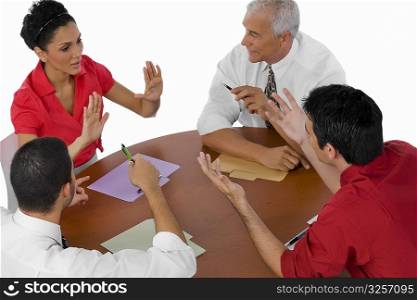 High angle view of three businessmen and a businesswoman discussing in a meeting