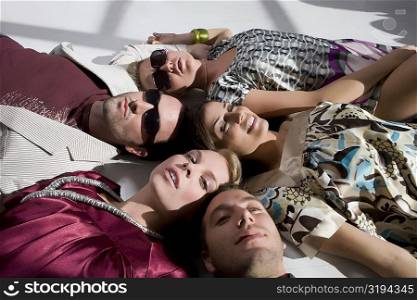 High angle view of three young women with two young men lying on the floor