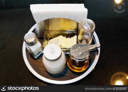 High angle view of tissue papers and a salt shaker with an oil bottle in a plate