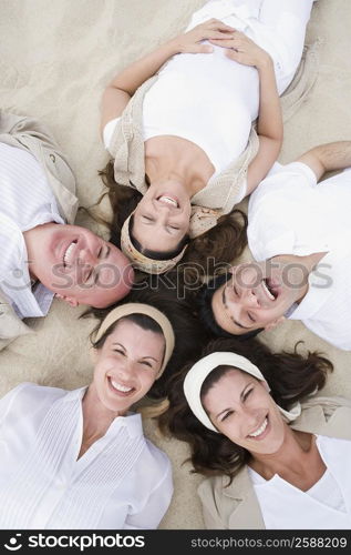 High angle view of two mature men with three mature women lying on sand