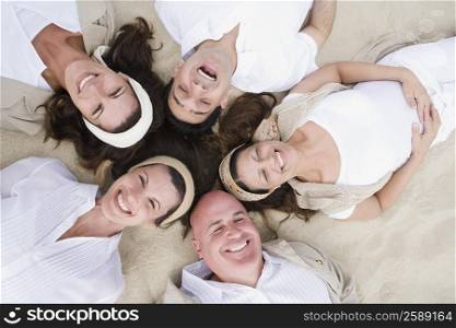 High angle view of two mature men with three mature women lying on sand