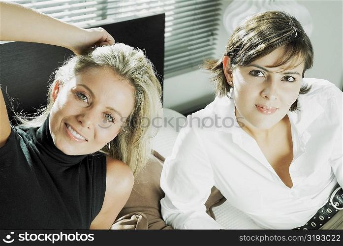 High angle view of two mid adult women reclining on the bed