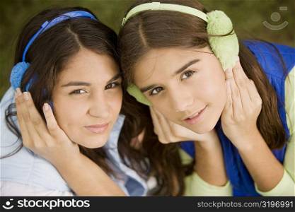 High angle view of two teenage girls covering their ears with earmuffs