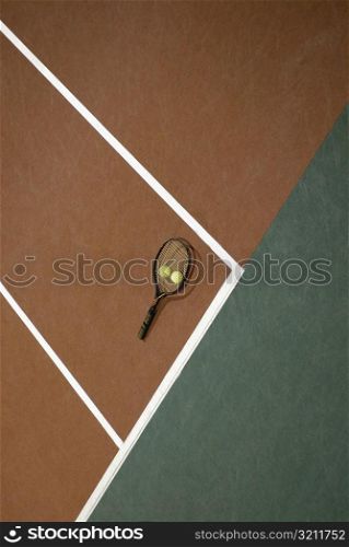 High angle view of two tennis balls and a tennis racket on a tennis court