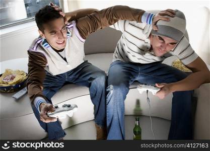 High angle view of two young men playing video game and rough housing