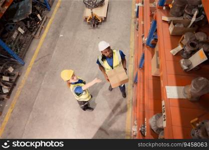 High angle view of warehouse workers in hardhats lifting boxes at warehouse