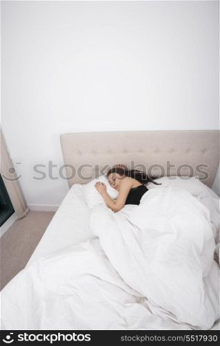 High angle view of young woman sleeping in bed