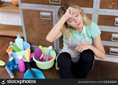 high angle view overworked cleaning woman sitting floor with cleaning tools products
