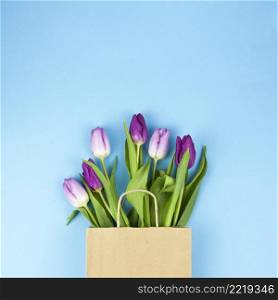 high angle view purple tulip flowers brown bag against blue backdrop