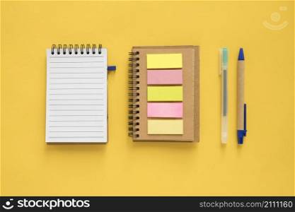 high angle view spiral notepad adhesive notes pen yellow background