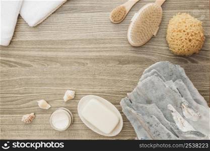 high angle view sponge seashell soap brush towel moisturizing cream wooden backdrop