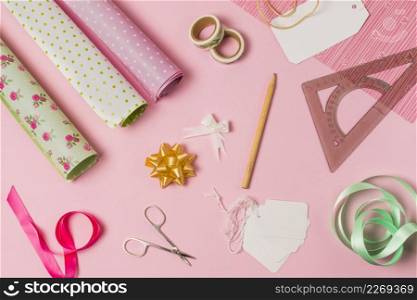 high angle view stationery supplies with gift wrap tags pink background
