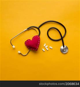 high angle view stethoscope stitched heart medicines yellow backdrop