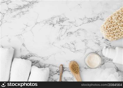 high angle view towels brush moisturizing cream sponge cosmetic bottle scrub glove marble surface