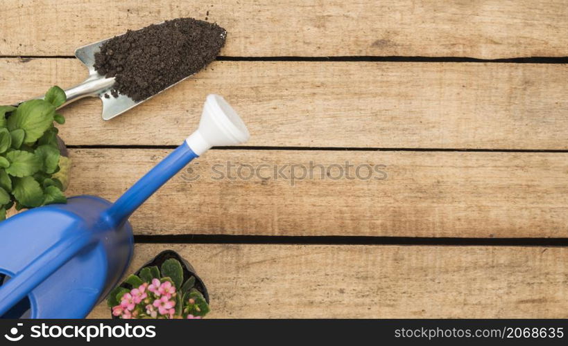 high angle view watering can flower potted plants hand shovel with soil wooden background