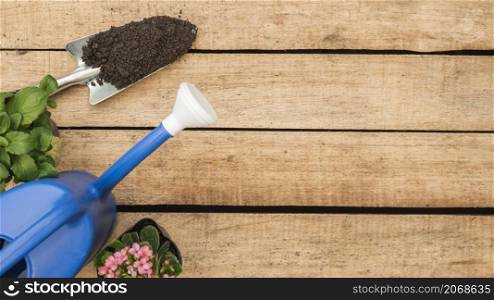 high angle view watering can flower potted plants hand shovel with soil wooden background