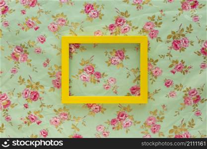 high angle view yellow empty frame against floral print background