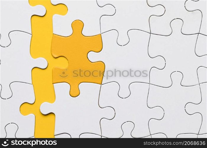 high angle view yellow puzzle piece arranged with white pieces