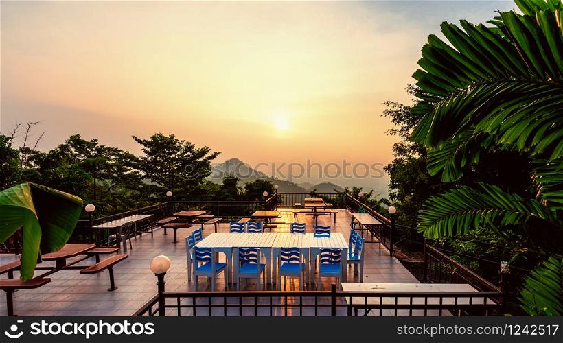 High angle viewpoint for watching the beautiful nature landscape colorful sky during the sunset. Table and chairs on the terrace for dining of the restaurant on the mountain, Chon Buri, Thailand, 16:9. Sunset viewpoint of the restaurant on the mountain