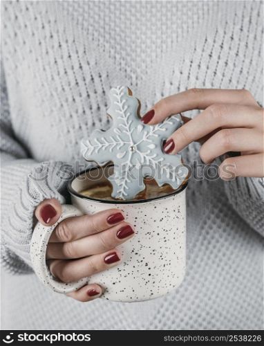 high angle woman dipping snowflake cookie hot chocolate