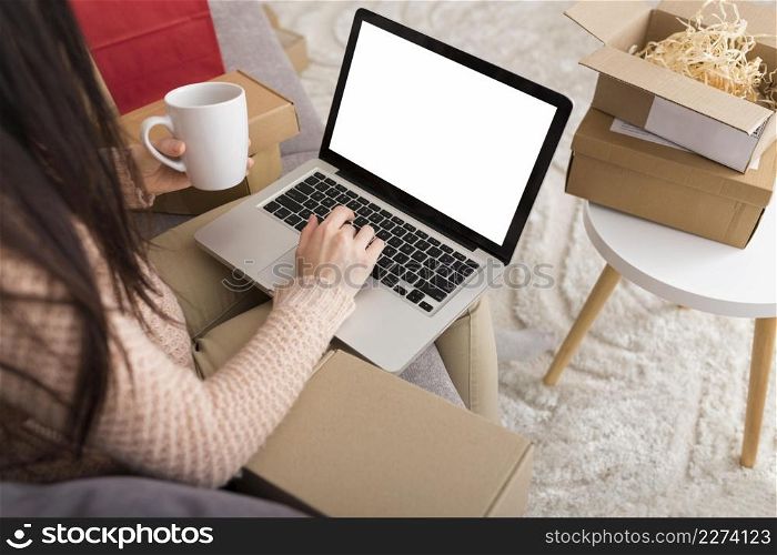 high angle woman sitting sofa while checking her laptop