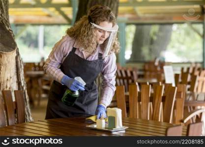 high angle woman with face protection cleaning tables