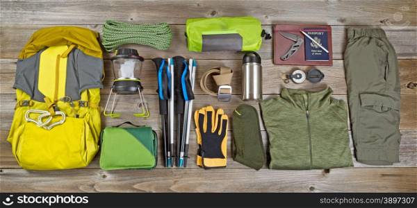 High angled view of organized hiking gear placed on rustic wooden boards in rectangle format.