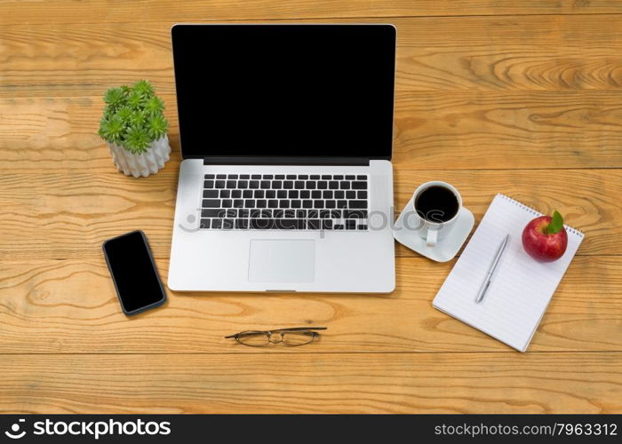 High angled view of simple desktop with mobile computer and cell phone with food and drink.