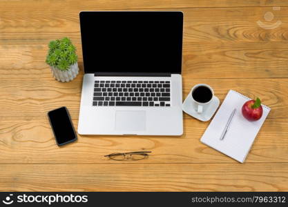 High angled view of simple desktop with mobile computer and cell phone with food and drink.