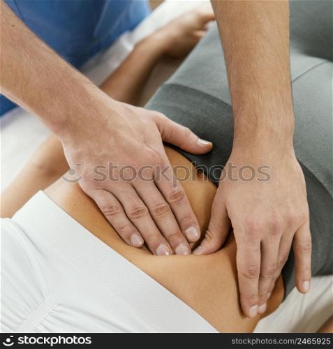 high angleof male osteopathic therapist checking female patient s abdomen