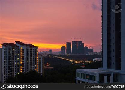High buildings under construction with cranes at evening with modern apartment living block of flats buildings .