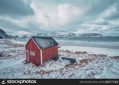 High Dynamic Range  HDR  image of red rorbu house shed on beach of fjord. Skagsanden beach, Lofoten islands, Norway. Red rorbu house shed on beach of fjord, Norway