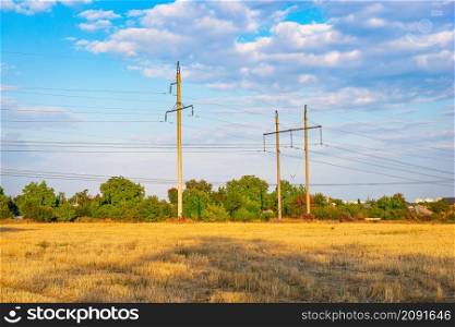 High electric poles on the field of mown wheat. High electric poles