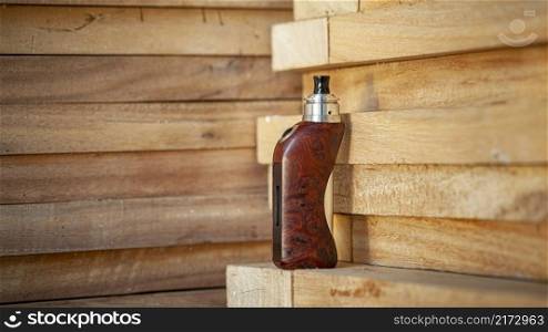 high end rebuildable dripping atomizer with stabilized natural redwood burl regulated box mods on natural wood texture background, vaping device, selective focus