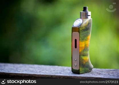 high end yellow green stabilized wood regulated box mods with rebuildable dripping atomizer on the old wood texture background, vaping device, selective focus