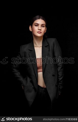 High fashion expressive portrait of young elegant woman in black suit and beige top. Studio shot. on a black isolated background