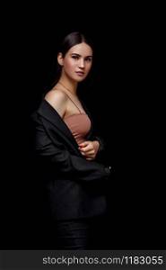 High fashion portrait of young elegant woman in black suit and beige top. Studio shot.